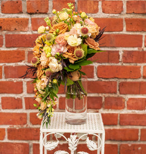 A gorgeous contemporary cascading wedding bouquet features Toffee roses, Sahara Sensation spray roses, stock, lisianthus, butterfly ranunculus, hypericum, scabiosa, agonis, salal, and Italian ruscus.