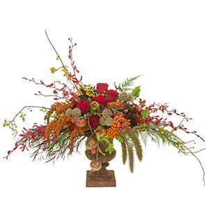 A lavish arrangement in Flemish style uses an oval design created from Kangaroo paw, chocolate phlox, roses, pomegranates, James story orchids, millet, amaranthus, agonis, scabiosa pods, montbretia pods, bittersweet, and helecho fern in a cast iron urn.
