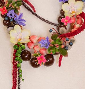 A gorgeous floral necklace mixes beads with pink hypericum berries, then it’s decorated with white micro mini phalaenopsis orchids, red hanging amaranthus, viburnum berries, kalanchoe florets, brunia, green String of Pearls, and blue hyacinth.