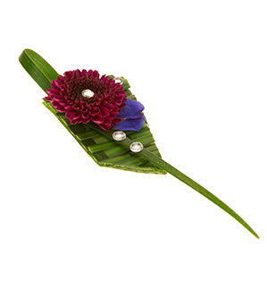 A modern prom wearable features green woven lily grass, red button poms, blue bella donna delphinium florets, and a little bit of bling.