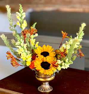 A crescent design arrangement in orange, yellow, and light green colors features sunflowers, snapdragons, craspedia, and kangaroo paws.