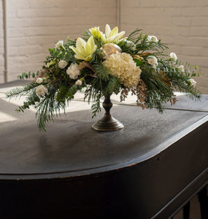 An elevated floral design mixes Douglas fir, cedar, Redwood sequoia with hydrangea, lilies, mini carnations, magnolia, eucalyptus, and boxwood.
