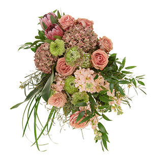 A gorgeous cascading bouquet in blush and peach hues mixes roses, stock, protea, hydrangea, ranunculus, seeded eucalyptus, Italian ruscus, aspidistra, Israeli ruscus, aralia leaves, and lily grass.