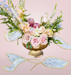 Arrangement in a gold vase with pink roses and faux leaves.