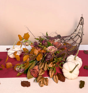 A lavish cornucopia made from barked wire and tinted tassel grass, overflowing with Coffee time roses, Cappuccino roses, chocolate brown lisianthus, tinted beech leaves, nandina, magnolia, and dried golden rain tree pods. 