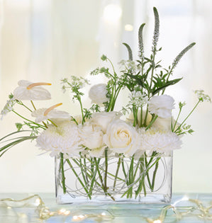 Modern all-white arrangement that features trending anthurium, elegant roses, ranunculus, and soft chrysanthemums.