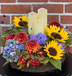 Thanksgiving centerpiece using golden sunflowers, richly textured autumn blooms, and safe, battery-operated candles.