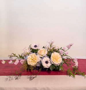 A lush horizontal centerpiece design using, Bessie garden roses, hydrangea, jasmine vine, pieris, sweet pea, anemone, and nerine lillies, all in soft pastels.
