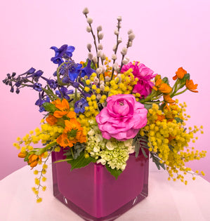 A vibrant colorful design full of miniature hydrangea, acacia, ranunculus, delphinium, ornithogalum, and pussy willow.