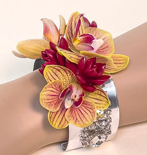 A sophisticated silver wrist cuff adorned with sparkly gems, miniature phalaenopsis orchids, and tinted succulents.