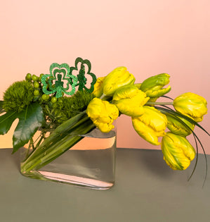 A simple yet elegant design created with tulips, green trick dianthus, hypericum berries, fatsia, lily grass, and adorned with sparkling shamrocks.
