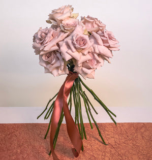 A mono-botanical wedding bouquet comprised of quicksand roses, that have been reflexed to give the bloom a larger face. Tied off with a warm copper ribbon and the stems left long and splayed out.