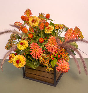 A textural design in a sunset color palette, made using Israeli ruscus, sedum, red-hot poker, gomphrena, zinnia, yarrow, hypericum and purple fountain grass.
