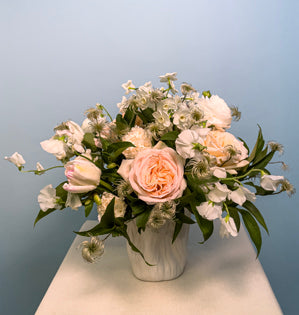A beautiful round arrangement blooming with Princess Maya garden roses, paper whites, tulips, eyelash clematis, sweet pea, ranunculus, and blush carnations.