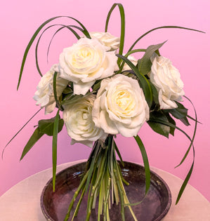 A elegant simple bouquet made using alabaster garden roses paired with stems of lily grass.