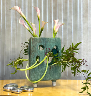 Calla lilies winding through a sculptural vase.