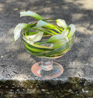 A beautiful centerpiece mixes ten stems of callas and one stem of flax in a footed glass compote.
