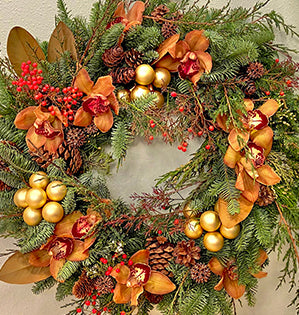 A luxurious and long-lasting wreath is created with evergreens, berries, pine cones, and bronze cymbidium orchids.