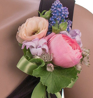 A beautiful corsage mixes lavender hyacinth with pink ranunculus and other delicate flowers and foliage. 