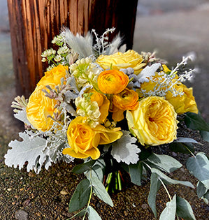 A hand-tied bouquet in the Pantone Colors of the Year 2021, Ultimate Gray and Illumination, features garden roses, ranunculus, stock, astrantia, brunia, kangaroo paws, and dusty miller.