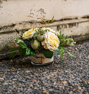 A rustic wedding centerpiece combines birch branches, seasonal grasses, eryngium, holly fern, privet, and flower pods with stunning Ashley garden roses.