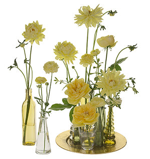 Lovely summer blooms in sunny yellow palette are placed in a variety of unique and colorful glass bottles, large and small, for a beautiful effect.