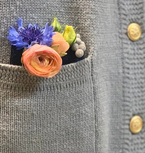 A casual contemporary corsage filled with beautiful blooms including ranunculus can be tucked into the pocket of a sweater or jacket for a stylish look.
