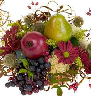 A contemporary cornucopia is a festive harvest centerpiece filled with grapes, pears, pomegranates, mums, scabiosa pods, carnations, solidago, fall leaves, rose hips, and a bit of flat wire for sparkle.