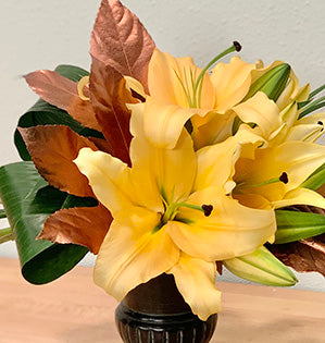 This lovely floral design mixes lilies, aspidistra, lily grass, and color enhanced crocodyllus and fatsia leaves for creative balance and beauty.