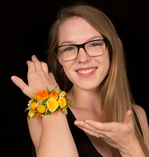 A gorgeous, over-the-top homecoming cuff with lots of bling is covered in orange roses, bright yellow spray roses, and sunshine colored craspedia for a beautiful style.