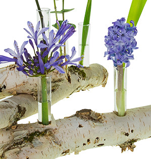 A closeup photo of a portion of the design featuring flowers in water tubes inserted into birch branches