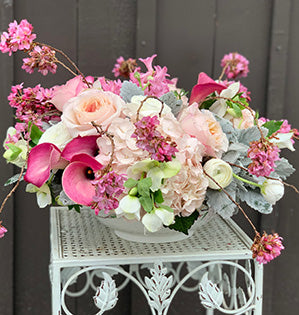 A beautiful monochromatic centerpiece mixes hellebores, hyacinth, miniature callas, garden roses and ranunculus.