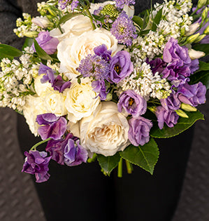 A lovely spring wedding bouquet mixes Princess Miyuki garden roses, Blanche spray roses, lilac, sweet peas, lisianthus, scabiosa, Italian ruscus, and fatsia leaves.