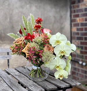 A stunning bouquet is filled with Toffee roses, Cappuccino roses, Queen Anne's lace, wax flower, butterfly ranunculus, and a variety of grasses.