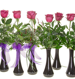Six black bud-vases, each holding single Blueberry roses with a combination of foliages like tree fern, ruscus, lily grass, Misty Latifolium, and fatsia leaves. The three vases to the left have bows tied of purple ribbon.