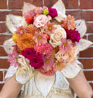 Bouquet featuring dahlias, roses, and soft textured blooms in trending peach and pink tones.