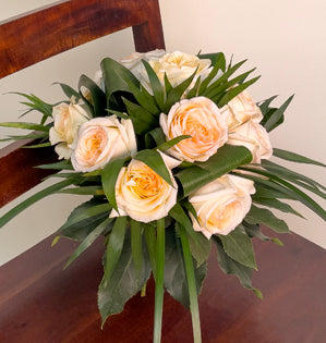 A simple but elegant spiral hand-tied bouquet made with, aspidistra, miniature palm, fatsia, lily grass and Princess Maya garden roses.