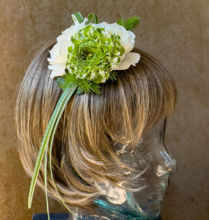 Mannequin head with blonde hair and a floral accessory on a brown background