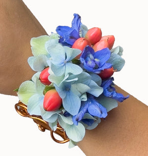 A hydrangea wrist corsage with soft blue hydrangea, vivid blue delphinium, and bright hypericum.