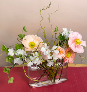 A natural vase design made with Poppies, hellebores, sweet peas, garden roses and curly willow.