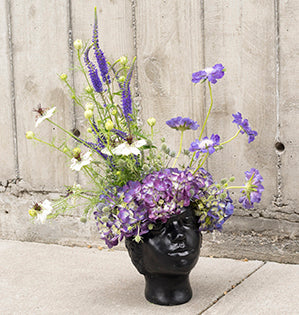 A dramatic ebony head vase with flowing purple flowers.