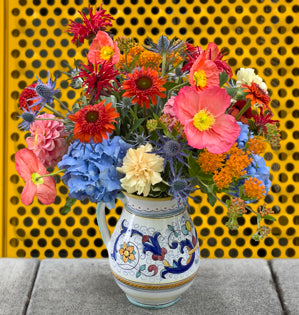 A beautiful Italian-inspired pitcher overflowing with poppies, hydrangea, asclepias, and other seasonal blooms.