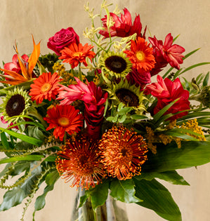 Bouquet of autumn flowers including sunflowers and red roses on a neutral background