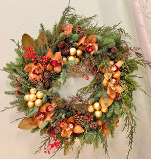 Decorative wreath with greenery, gold ornaments, and red berries on a light background