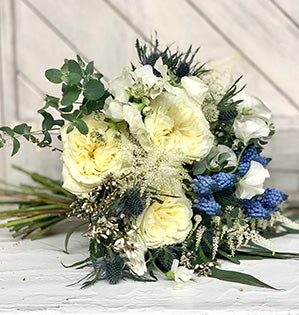 Bouquet of white and yellow flowers with greenery on a wooden surface